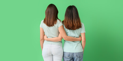 Beautiful hugging women on green background, back view