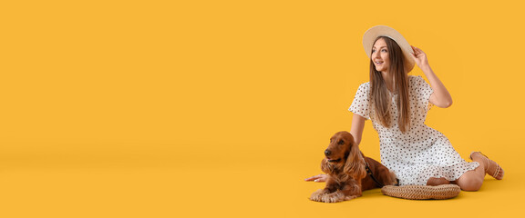 Sitting young woman with red cocker spaniel on yellow background with space for text