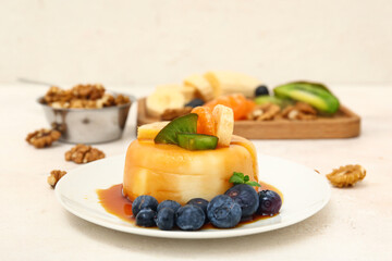 Delicious pudding with fruits and blueberries covered by caramel syrup on white table