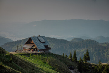 Beautiful alpine hut on Golica mountain visible from above. Nice forest in the background. Slovenian alpine cottages surrounded by green scenery
