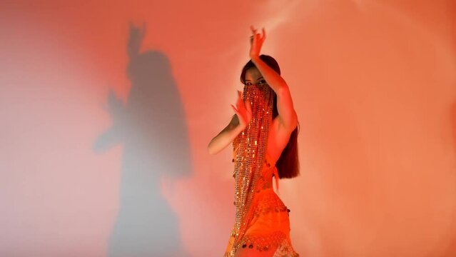 Young woman dancing oriental arabic dance. Pretty belly dancer in orange dress.