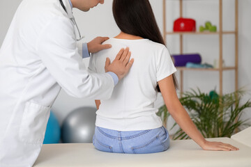 Male doctor checking posture of young woman in clinic