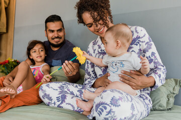 Latin family father and mother with children laughing and having fun together on bed at home in Mexico Latin America, hispanic people