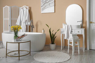 Interior of bathroom with bathtub, dressing table and narcissus flowers