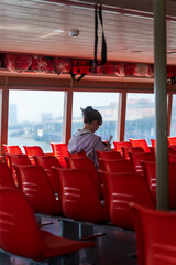 A lonely girl sitting alone on the ferry, the scene bright but somewhat sad