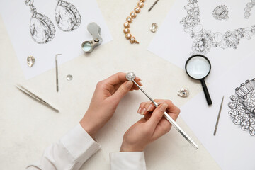 Female jeweler making ring on white table, closeup - obrazy, fototapety, plakaty
