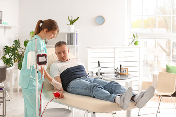 Female nurse taking blood from mature donor in clinic