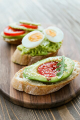 Board of tasty bruschettas with avocado on wooden background
