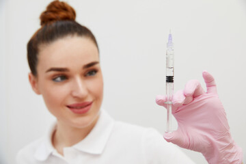 Cosmetologist holds syringe for injection with collagen hyaluronic filler for face or lips rejuvenation