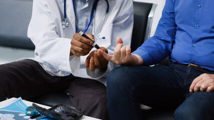 Fototapeta premium African american doctor doing medical test with diabetic man in hospital lobby, measuring insulin level and glucose in blood sample using glucometer. Seniorman having checkup visit appointment