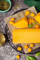 Stand with tasty cheddar cheese and herbs on grunge background