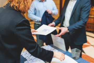 Process of checking in on a conference congress forum event, registration desk table, visitors and attendees receiving a name badge and entrance wristband bracelet and register electronic ticket