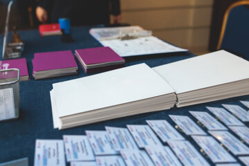 Fototapeta premium Registration desk table, process of checking in on a conference congress forum event, visitors and attendees receiving a name badge and entrance wristband bracelet and register electronic ticket