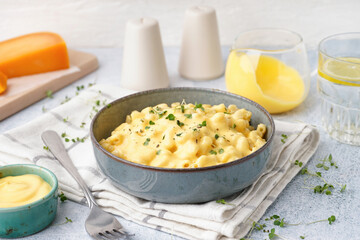 Bowl of tasty Italian pasta with Cheddar cheese on light background