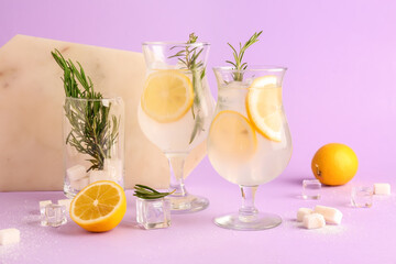 Glasses with fresh lemonade and rosemary on lilac background