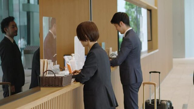 ホテルにチェックインする出張するビジネスマンたち