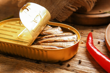 Canned smoked sprats with chilli on wooden background