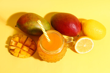 Mason jar of fresh mango smoothie and lemon on orange background
