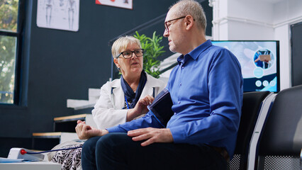 Elderly doctor using tonometer instrument to measure old patient pulse pressure and hypertension,...