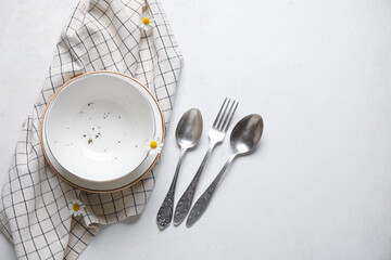 Plates with silver cutlery and napkin on grunge white background