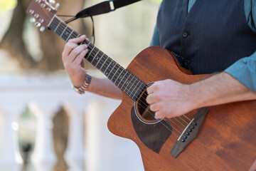 Fototapeta premium Professional guitarist plays guitar outdoors. Musician plays a classical guitar in the park.