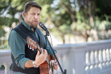 Musician man playing guitar and singing in the street