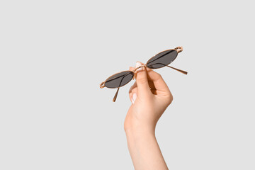Female hand holding stylish sunglasses on white background