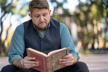 Business man reading a book in a park