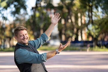 Man pointing with his hands to the side and smiling at camera outdoors