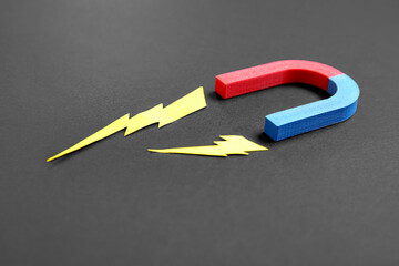 Paper lightnings with horseshoe shaped magnet on black background