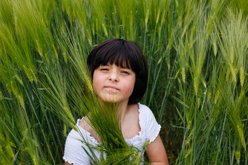portrait of smiling girl with dark hair sitting in a field of wheat