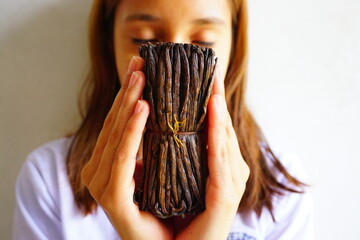 Close up of a girl holding vanilla beans in her hands and enjoying its aroma