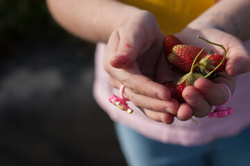 mano de niña con anillo de juguete sujetando fresas silvestres