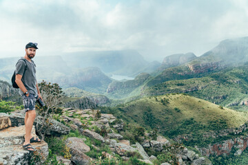 Naklejka premium Wide shot of a man on a cliff with a the view from the top of the blyde river canyon in South Africa.