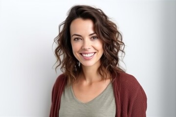 Fototapeta premium Portrait of smiling young woman with curly hair, looking at camera, standing against white wall.