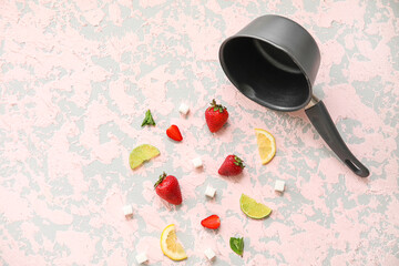 Saucepan and ingredients for preparing strawberry compote on pink grunge background