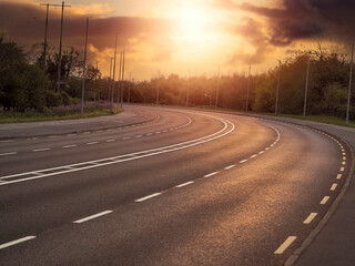 Empty two line motor way at sunrise of sunset. Warm orange color tone, light reflection on high quality asphalt road surface. Transportation industry. Nobody. Calm mood.