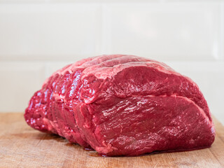 Big size beef top side joint on a wooden cutting board. Premium high quality meat. Traditional meal for a big family dinner. Light and airy look.