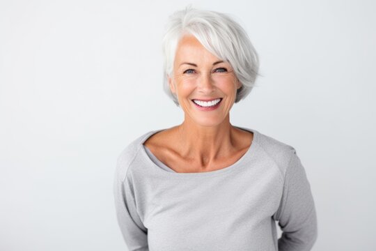 Lifestyle portrait photography of a grinning woman in her 60s on a white background