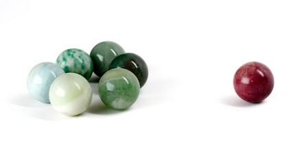 A lone marble excluded from a small group of  other, similarly colored marbles.