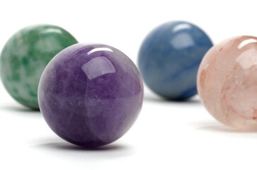 Selective focus closeup on a polished violet marble, with other vibrantly colored marbles in the background.