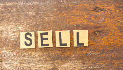 The word sell formed with wooden blocks on a rustic background.