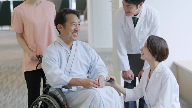 病院で車椅子に乗った入院患者と話す医者