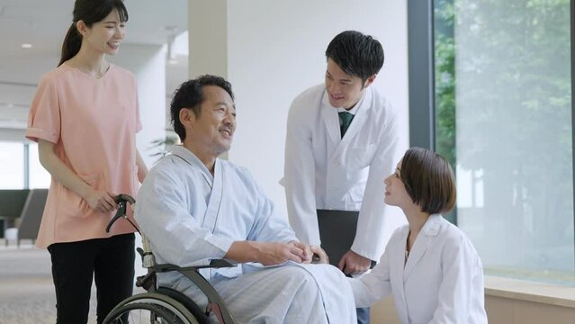 病院で車椅子に乗った入院患者と話す医者