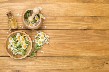 Obraz na płótnie Canvas Composition with essential oil and chamomile flowers on wooden background, top view