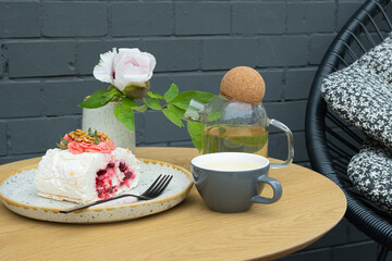 Meringue roll with a cup of buckwheat tea on a table in an outdoor cafe. Sweet food Still life