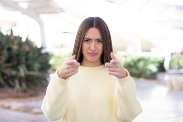 Fototapeta premium young pretty woman pointing forward at camera with both fingers and angry expression, telling you to do your duty