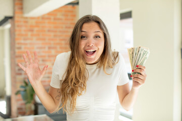 pretty woman feeling happy and astonished at something unbelievable. dollar banknotes concept