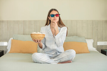Obraz premium young pretty woman smiling with a happy, confident expression with hand on chin. popcorns and movie concept