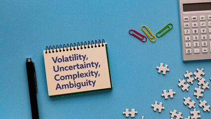 There is notebook with the word Volatility, Uncertainty, Complexity, Ambiguity. It is as an...